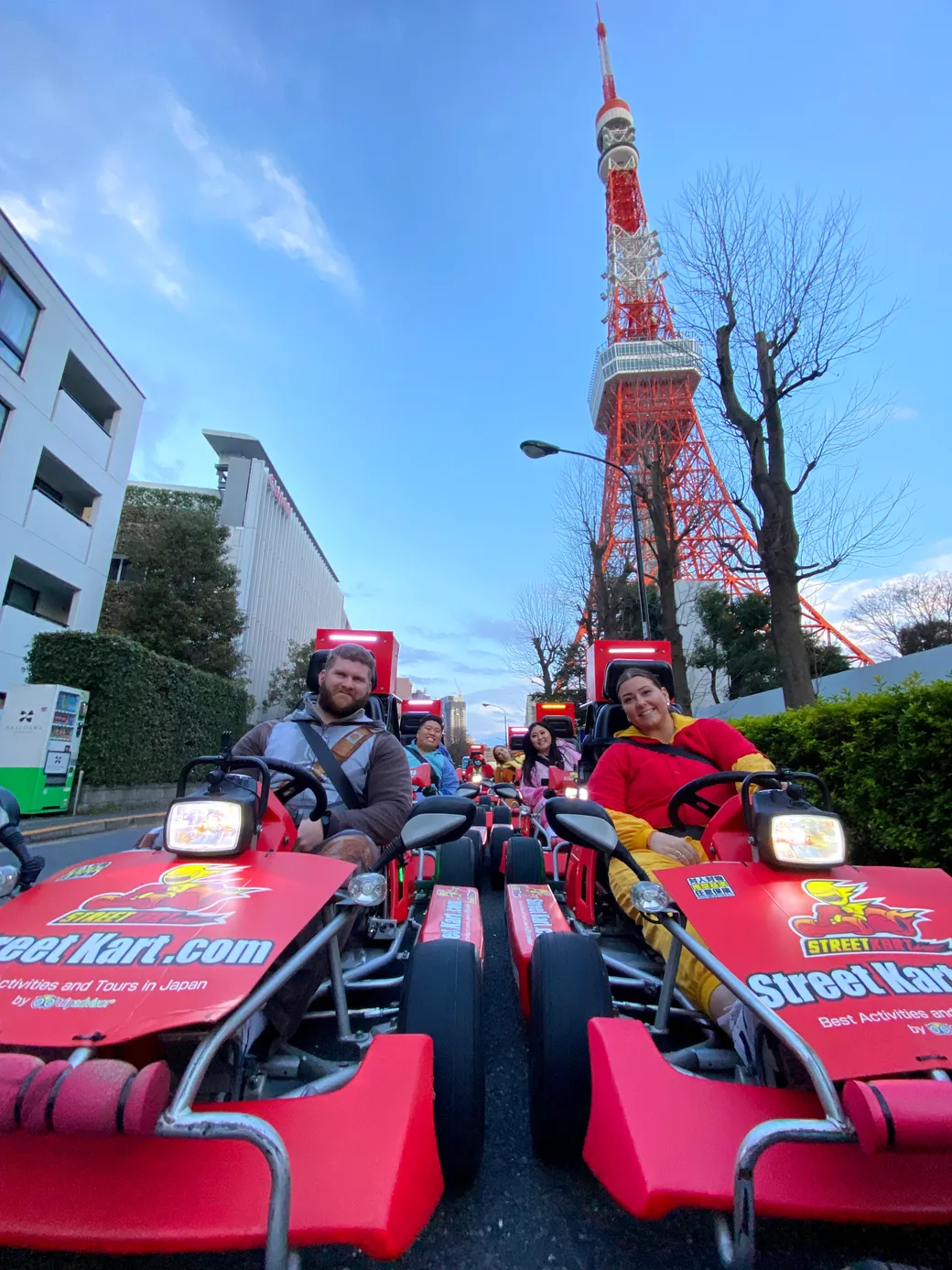 People ride red Street Kart go-karts down a city street with Tokyo Tower in the background.